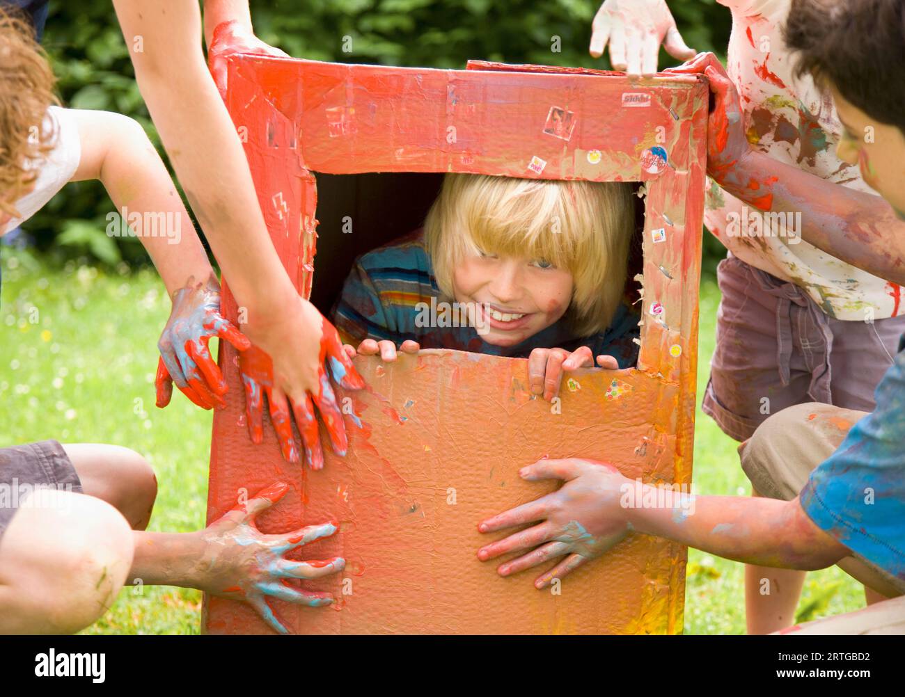 Blonde junge gefangen in einem Karton mit Freunden zu spielen Stockfoto