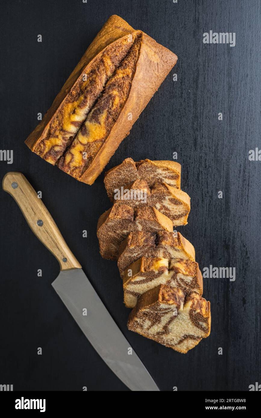 Marmor-Biskuitkuchen. Kuchen mit Kakao- und Vanillegeschmack auf dem schwarzen Tisch. Draufsicht. Stockfoto
