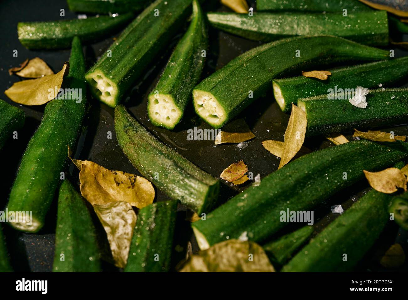 Schließen Sie leuchtend grünes Okra und lassen Sie in der Pfanne mit Öl und Salz kochen Stockfoto