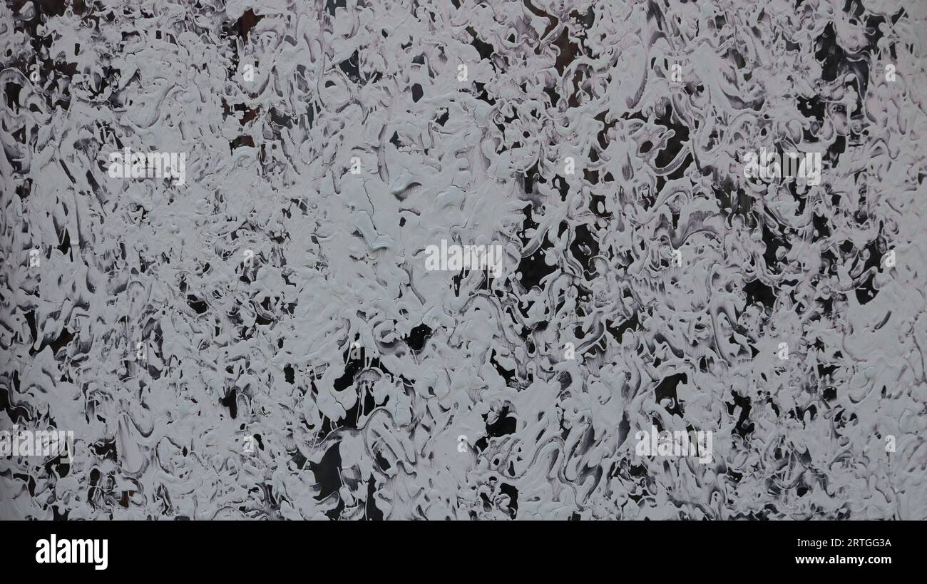 Dichromatischer Schwarz-weiß-Hintergrund mit einem kunstvollen Muster und Wirbeln von weißen Farben auf dunklem Glas, grafische Abstraktion mit einem chaotischen Muster Stockfoto