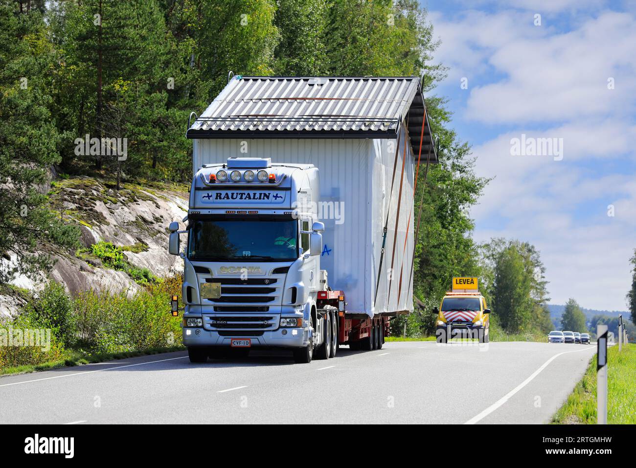 Überdimensionaler Lasttransport von vorgefertigter Kabine durch Scania R560 Lkw-Auflieger, Begleitfahrzeug-Unterstützung. Salo, Finnland. September 2023. Stockfoto