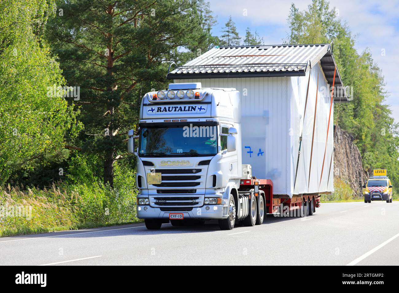 Überdimensionaler Lasttransport von vorgefertigter Kabine durch Scania R560 Lkw-Auflieger, Begleitfahrzeug-Unterstützung. Salo, Finnland. September 2023. Stockfoto