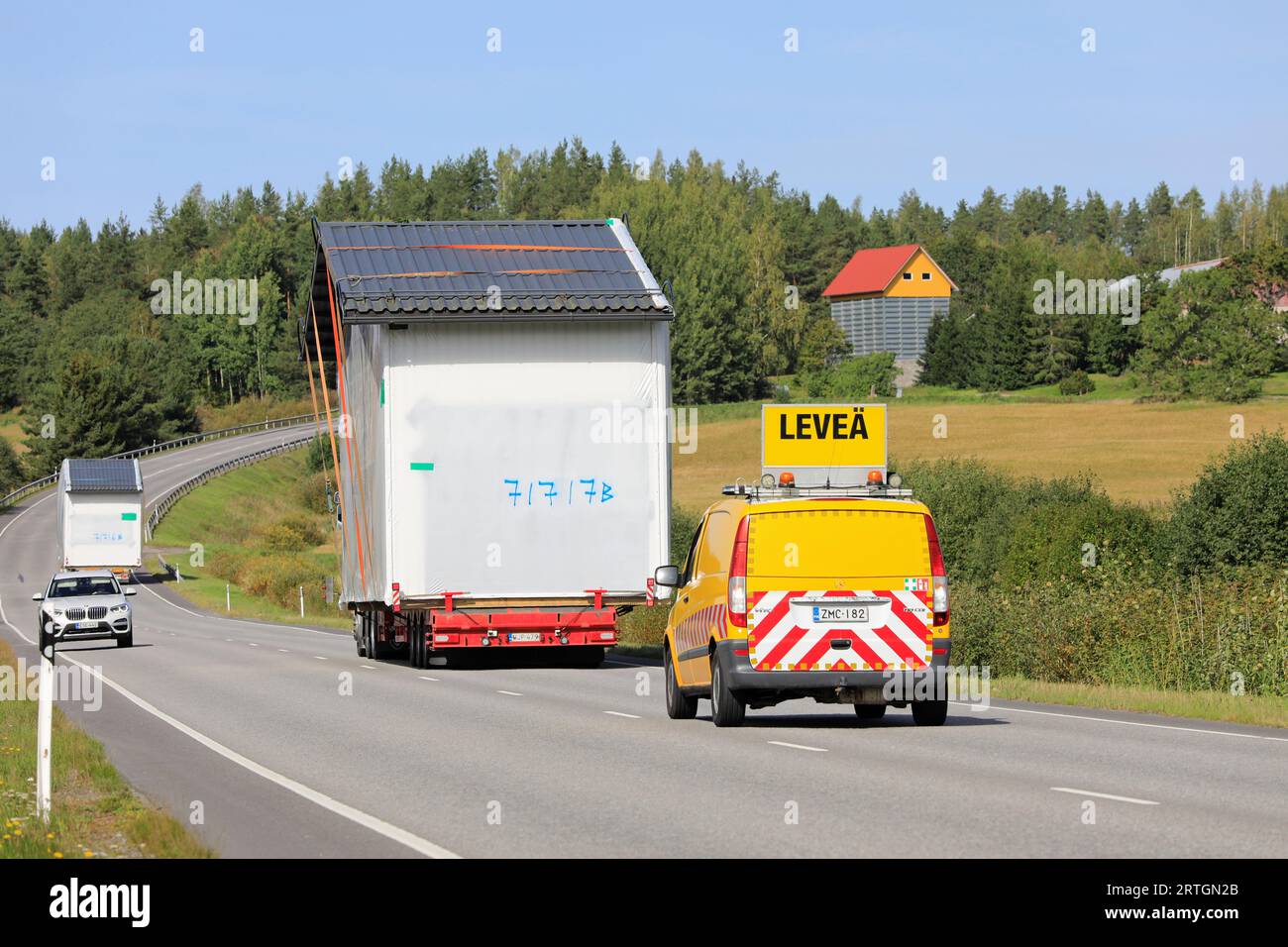 Zwei außergewöhnliche Lasttransporte einer vorgefertigten Kabine im Straßenverkehr, Begleitfahrzeug-Unterstützung, Auto macht Platz. Salo, Finnland. September 2023. Stockfoto