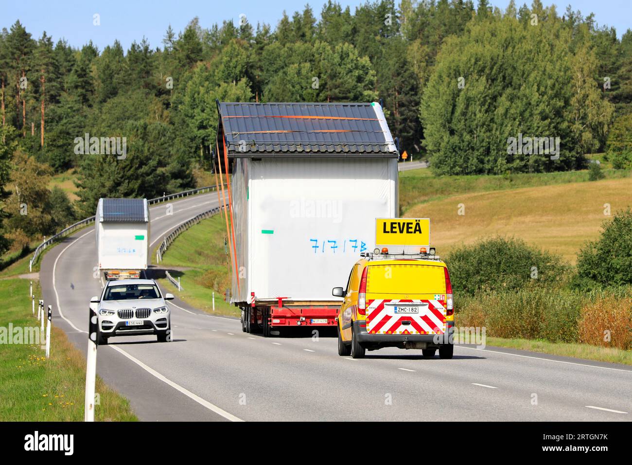 Zwei außergewöhnliche Lasttransporte einer vorgefertigten Kabine im Straßenverkehr, Begleitfahrzeug-Unterstützung, Auto macht Platz. Salo, Finnland. September 2023. Stockfoto