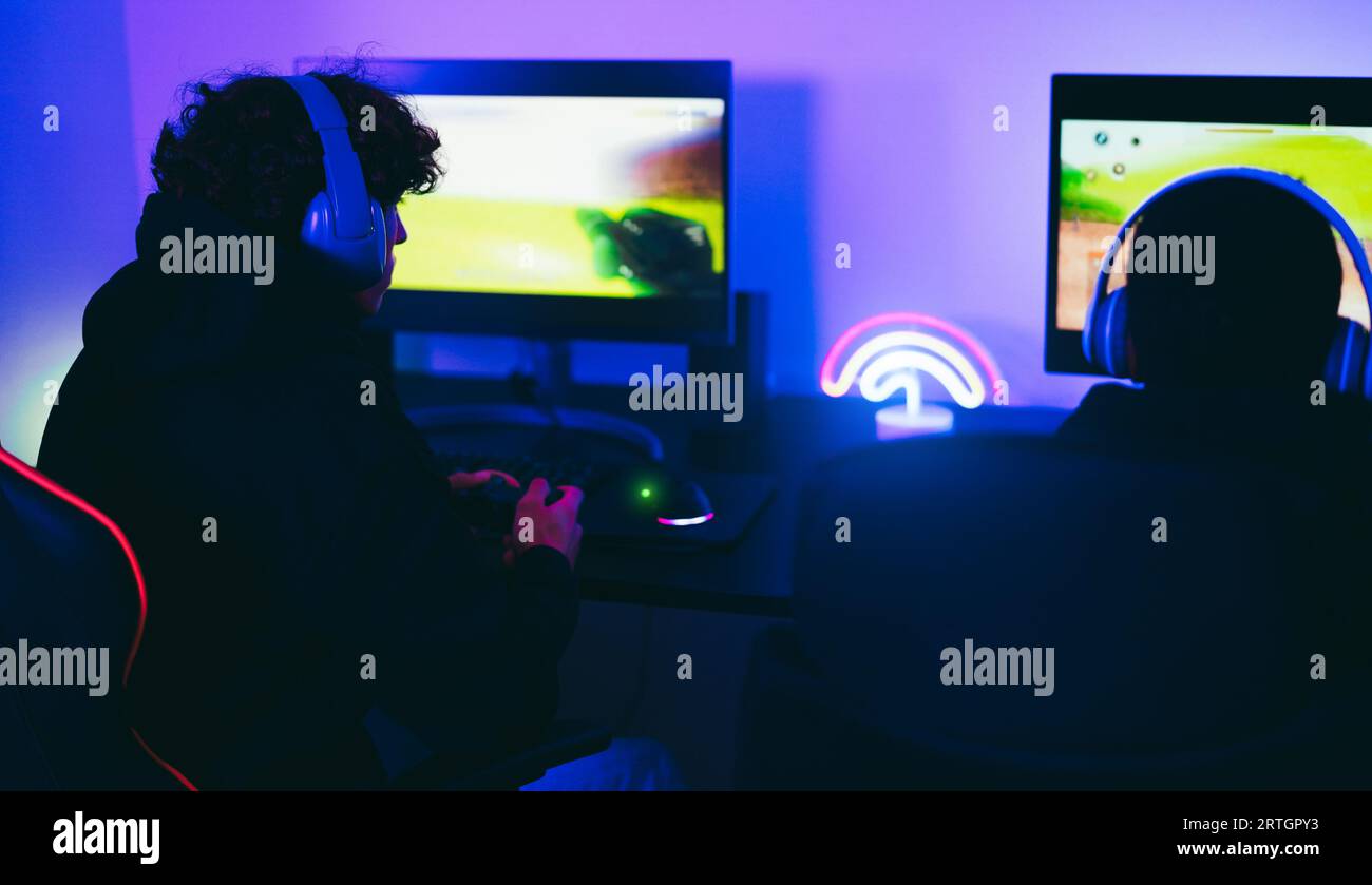 Junge Gamer, die beim E-Sport-Wettbewerb beim offiziellen Turnier spielen – neue Technologie, Spieltrends und Unterhaltungskonzept – konzentrieren sich auf linke Kopfhörer Stockfoto