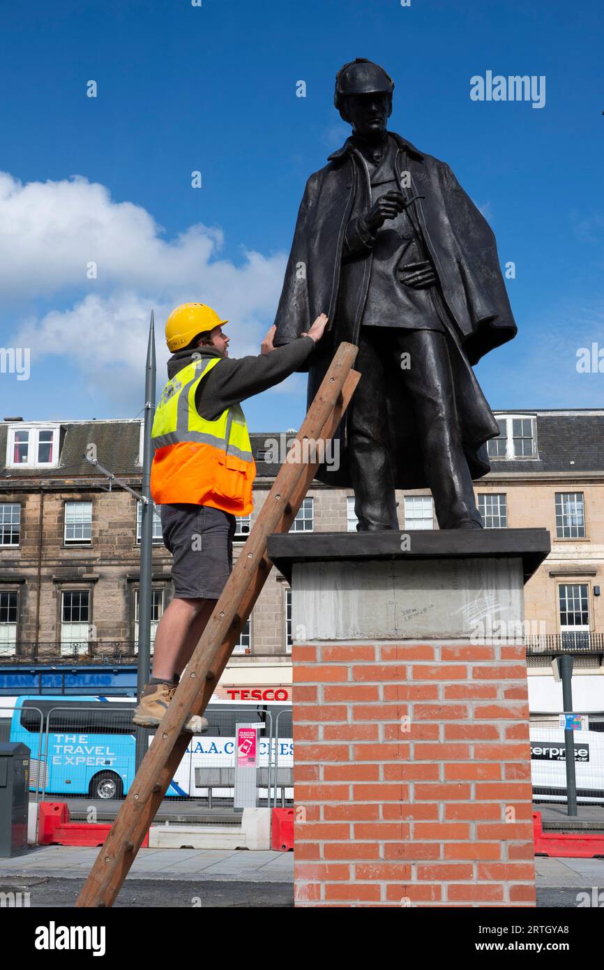 Edinburgh, Schottland, Großbritannien. September 2023. Die neu renovierte Statue von Sherlock Holmes wurde heute von Sir Arthur Conan Doyles Verwandter Tania Henzell und dem Verkehrskonventor Scott Arthur an einem neuen Ort am Picardy Place enthüllt. Die lebensgroße Bronzeskulptur, die den Geburtsort des Schöpfers des Supersleuth, Sir Arthur Conan Doyle, markiert, wurde 2018 entfernt, während Straßenbahnen zu Newhaven-Werken durchgeführt wurden. Es wurde von Black Isle Bronze in Nairn renoviert. Bild: Die Arbeiter machen den Sockel mit der Statue zum letzten Schliff. Iain Masterton/Alamy Live News Stockfoto