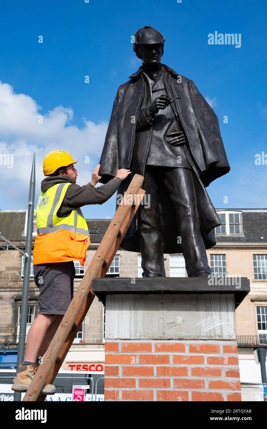 Edinburgh, Schottland, Großbritannien. September 2023. Die neu renovierte Statue von Sherlock Holmes wurde heute von Sir Arthur Conan Doyles Verwandter Tania Henzell und dem Verkehrskonventor Scott Arthur an einem neuen Ort am Picardy Place enthüllt. Die lebensgroße Bronzeskulptur, die den Geburtsort des Schöpfers des Supersleuth, Sir Arthur Conan Doyle, markiert, wurde 2018 entfernt, während Straßenbahnen zu Newhaven-Werken durchgeführt wurden. Es wurde von Black Isle Bronze in Nairn renoviert. Bild: Die Arbeiter machen den Sockel mit der Statue zum letzten Schliff. Iain Masterton/Alamy Live News Stockfoto