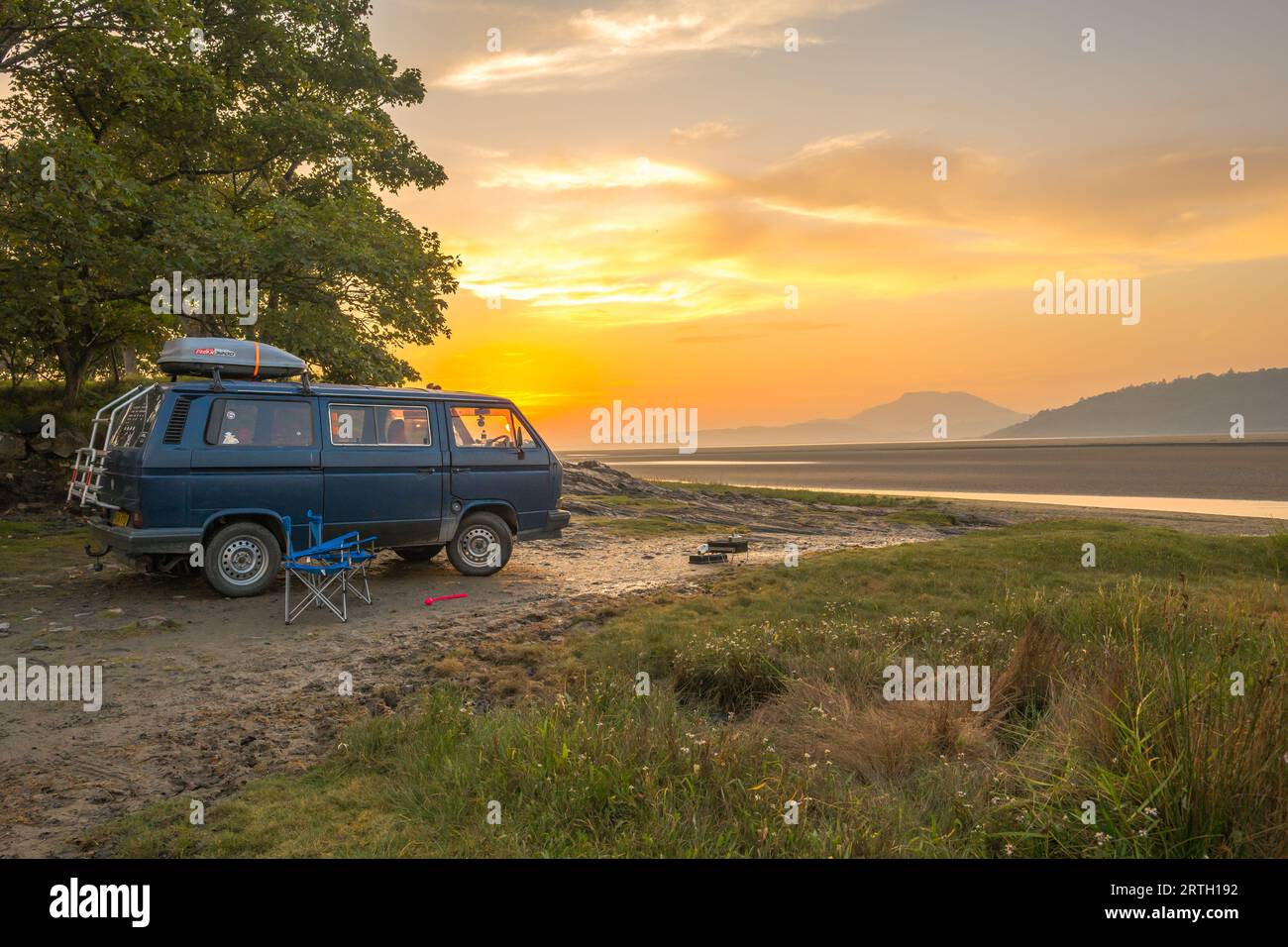 Sonnenuntergang am Traeth Bach mit blauem Himmel und ruhigem Meer mit VW-Campervan Stockfoto