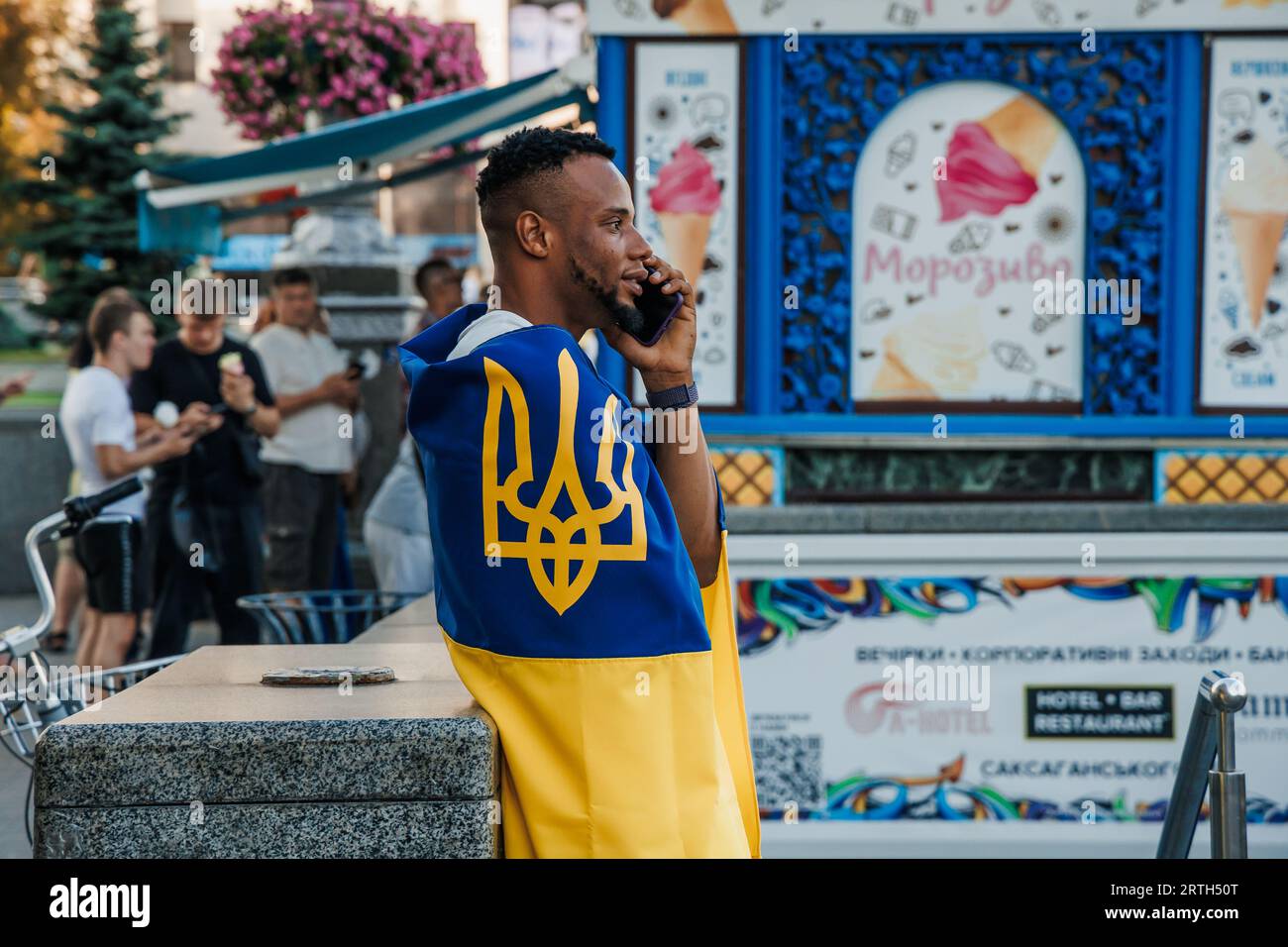 Ein dunkelhäutiger junger Mann trägt die Flagge der Ukraine mit Tryzub auf der Straße Chreshchatyk während der Feier des Unabhängigkeitstages der Ukraine Stockfoto