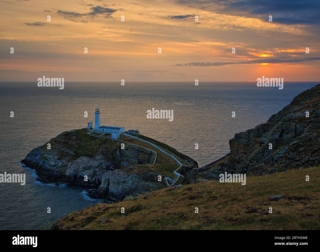 Der Sonnenuntergang über dem South Stack Lighthouse auf der Isle of Anglesey ist bei letztem Licht zu sehen. Stockfoto