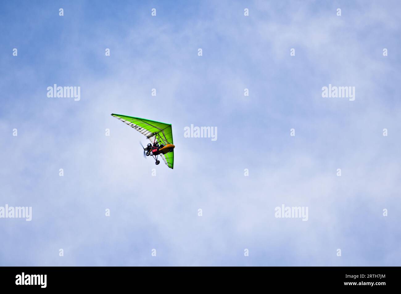 Mann auf grünem motorisiertem Drachenflieger genießt seinen Flug. Stockfoto
