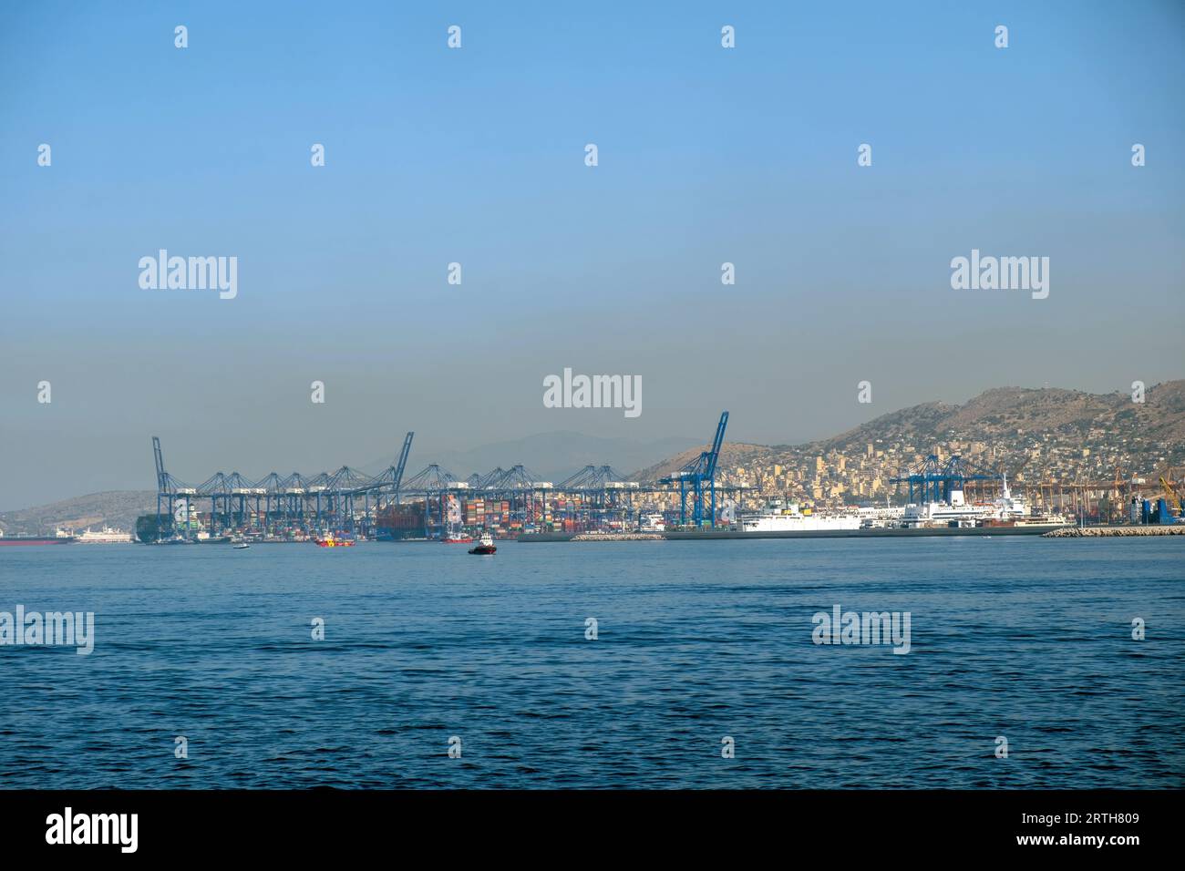 Hafen von Piräus, Attika Griechenland. Industriegebiet, Containerterminal, festgelegtes Frachtschiff zum Be- oder Entladen. Mediterranes Meer, blauer Himmel Hintergrund. Stockfoto