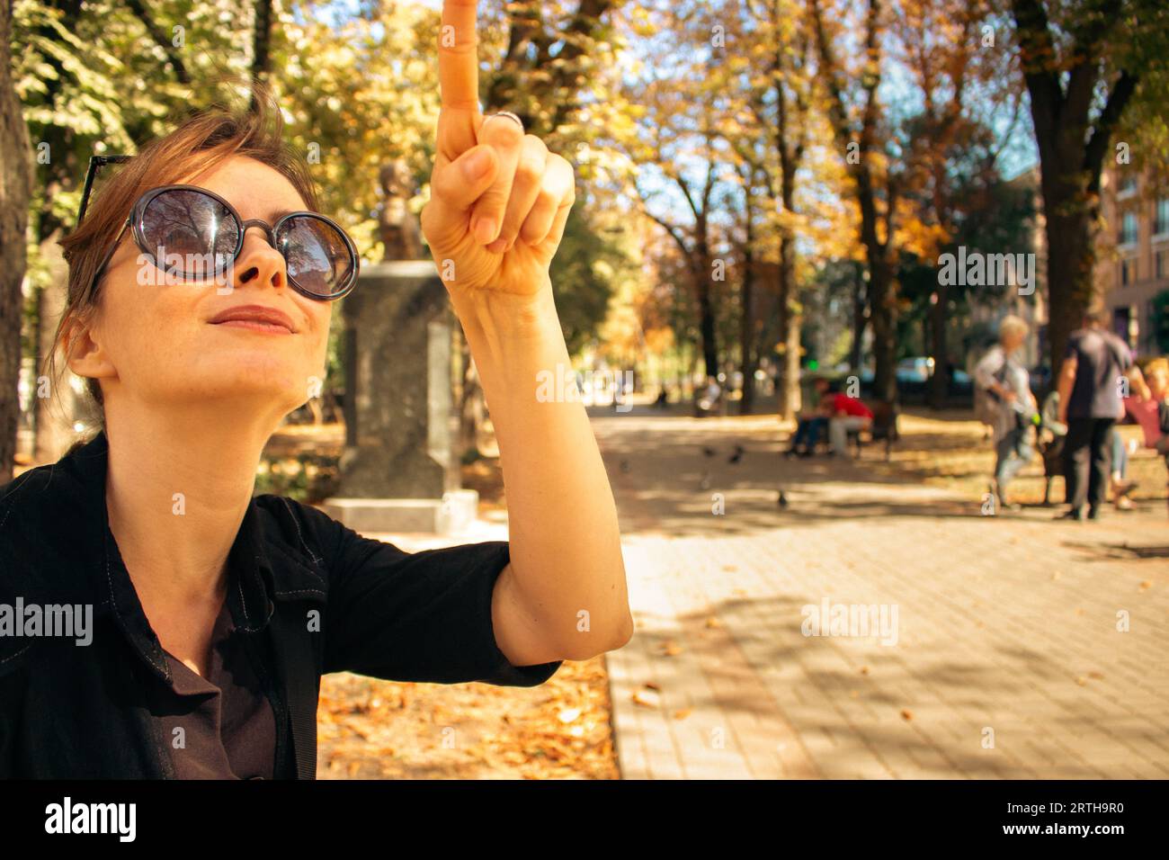 Mädchen in Sonnenbrille auf der Bank im Park. Attraktive Frau in der Herbstgasse. Frauenporträt in Sonnenbrille. Herbst in Downtown. Street Lifestyle. Stockfoto