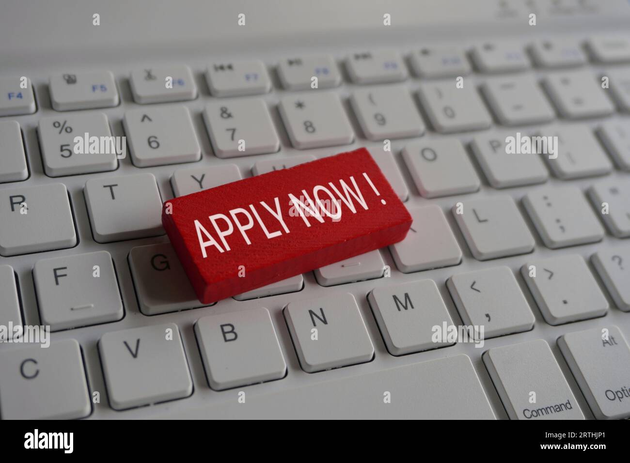 Nahaufnahme eines Holzwürfels mit Text JETZT BEWERBEN! Auf der Computertastatur. Stockfoto