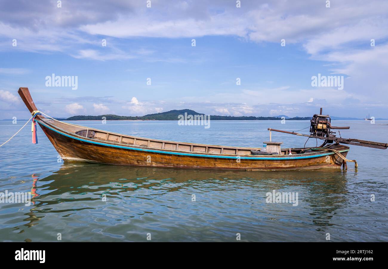 Langboot wartet auf Passagiere auf der wunderschönen Insel Ko Lanta, Thailand. Die Wolken und das Boot umrahmen ein Stück blauen Himmel ein Leerzeichen Stockfoto