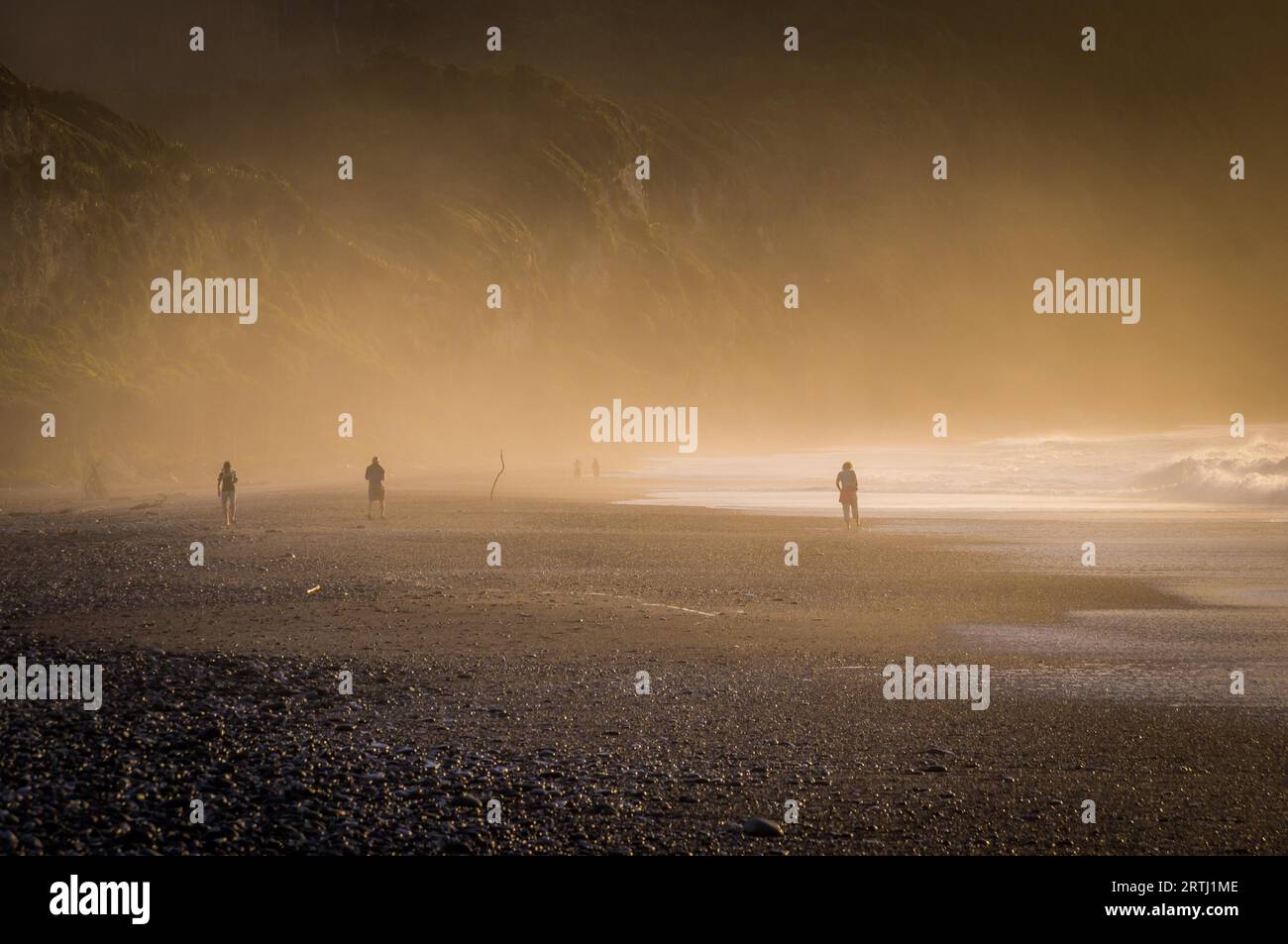 South Island, Neuseeland am 16. Februar 2016: Ein Kiesstrand auf Neuseelands Südinsel bei Punakaiki ist mit Nebel bedeckt, während die Sonne untergeht Stockfoto