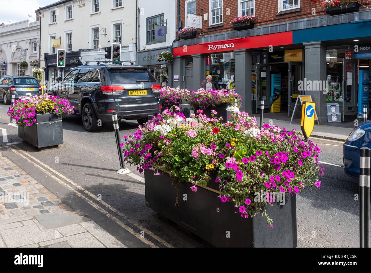 Verkehrsberuhigung, Pflanzgefäße mit Blumen auf der Straße, um sie zu schmälern und langsamer Verkehr, Farnham Stadtzentrum, Surrey, England, Großbritannien Stockfoto