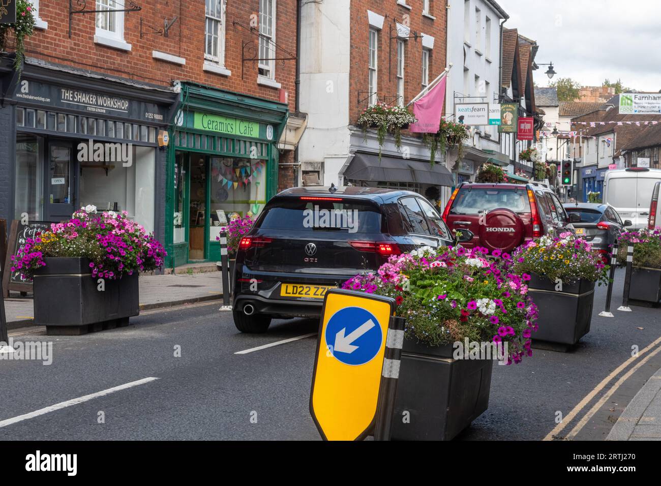 Verkehrsberuhigung, Pflanzgefäße mit Blumen auf der Straße, um sie zu schmälern und langsamer Verkehr, Farnham Stadtzentrum, Surrey, England, Großbritannien Stockfoto