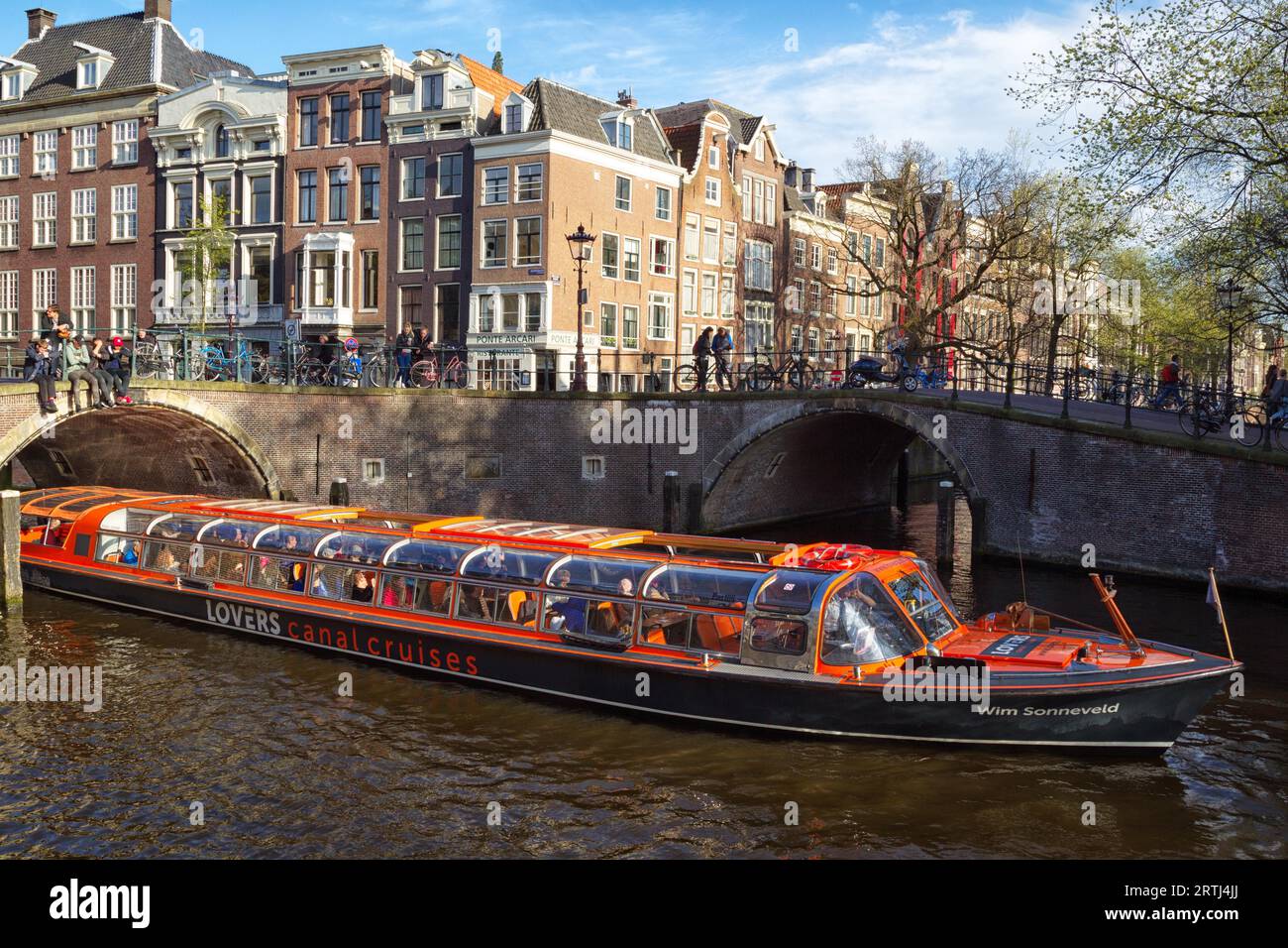 Stadtbesichtigung in einem Boot auf einem Kanal in Amsterdam, Niederlande im Frühjahr. Sightseeing-Boot auf einem Kanal in Amsterdam, Niederlande im Frühling Stockfoto