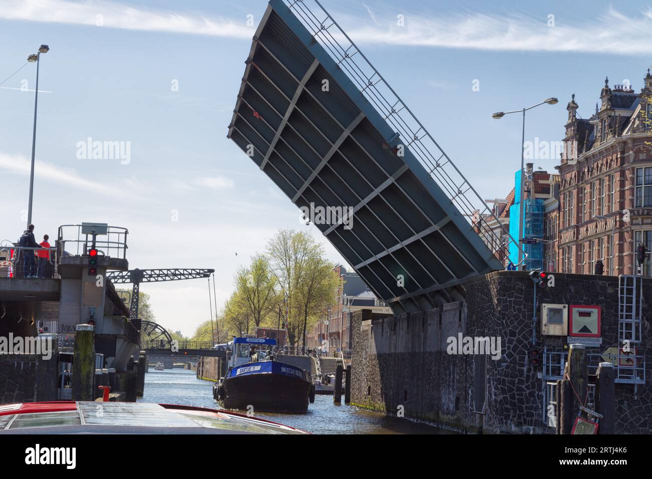 Schiff, das im Frühjahr unter einer offenen Zugbrücke in Amsterdam, Niederlande, vorbeifährt Stockfoto