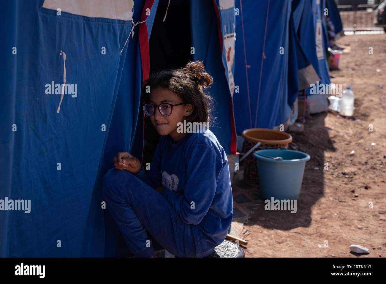 Marokko. September 2023. Ein Mädchen sitzt vor einem Zelt und dient als provisorisches Zuhause für Menschen, die ihre Häuser durch das Erdbeben verloren haben. Die Dorfbewohner in Imlil in den Toubkal-Bergen kommen noch immer mit der Zerstörung zurecht, die das Erdbeben am vergangenen Freitag angerichtet hat. Da viele Häuser beschädigt oder zerstört wurden, wurden Dorfbewohner in Zelte verlegt und werden von Ärzten aus einem nahe gelegenen Militärkrankenhaus in Asni betreut, wo täglich etwa 600 Menschen behandelt werden. Fast 3.000 Menschen sollen bei dem Erdbeben ums Leben gekommen sein. (Bild: © Ashley Chan/SOPA Images über ZUMA Press Stockfoto