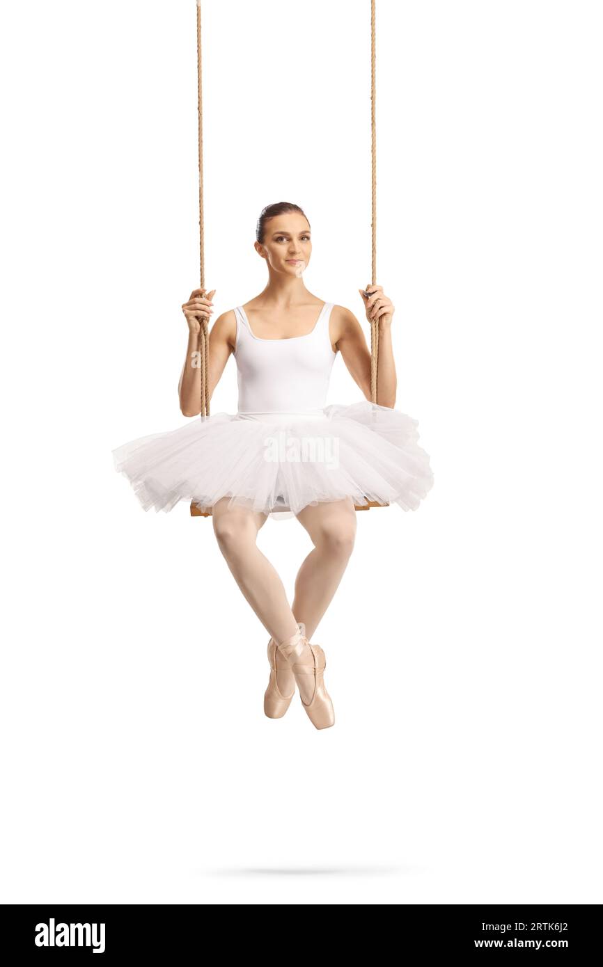 Wunderschöne Ballerina in einem weißen Kleid, die auf einer Holzschaukel auf weißem Hintergrund sitzt Stockfoto