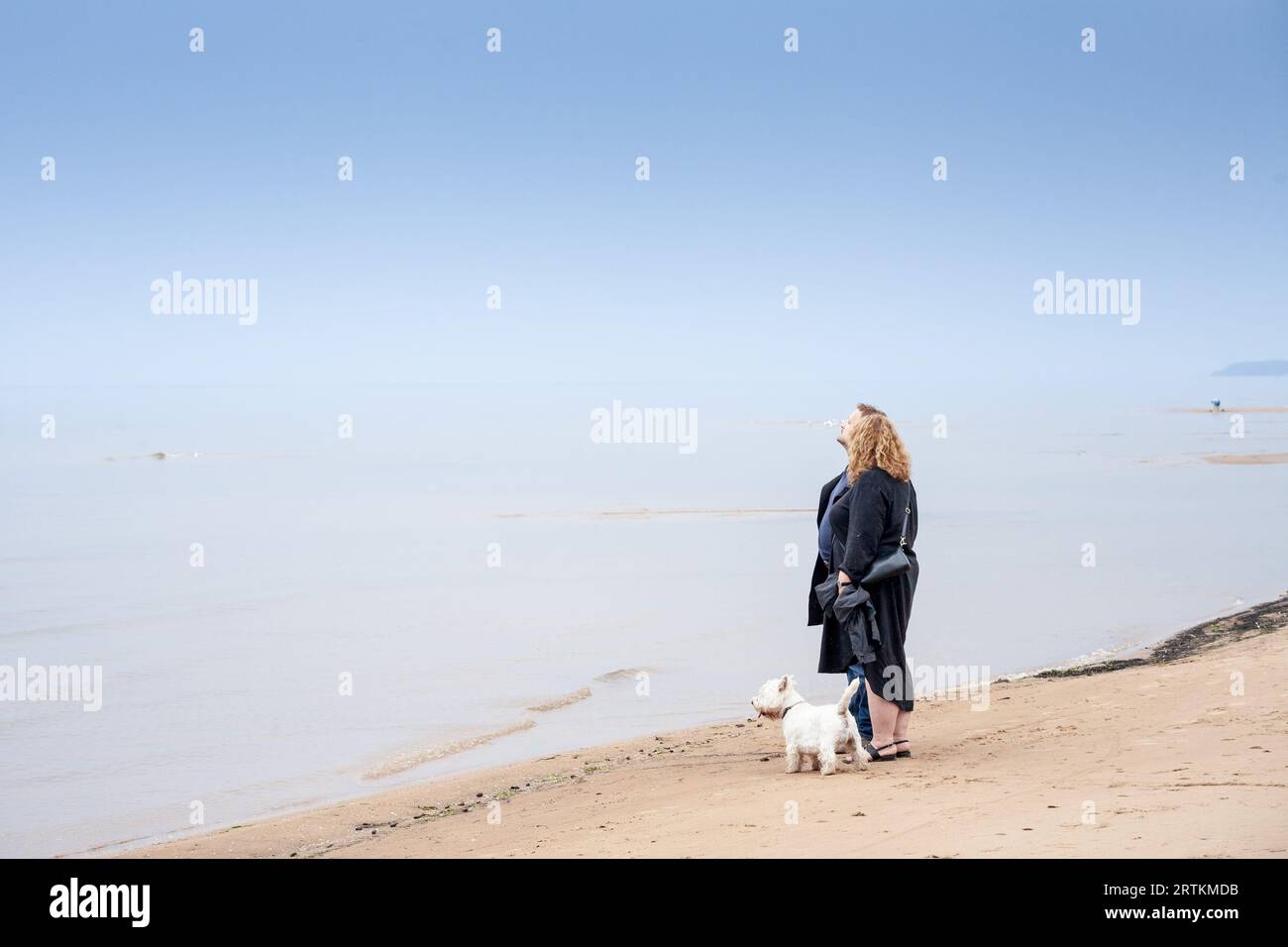 Bild eines Paares, das eine Meereslandschaft in Garciems, Lettland, mit einem nebligen Horizont im Hintergrund beobachtet. Stockfoto