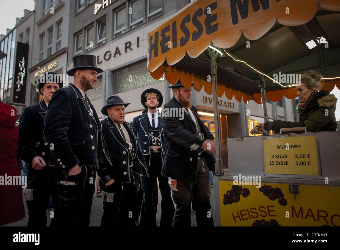 Bild von Menschen in Kostümen für den Kölner Karneval stehend und geröstete Kastanien in Köln, Deutschland. Kölner Karneval (Kö Stockfoto