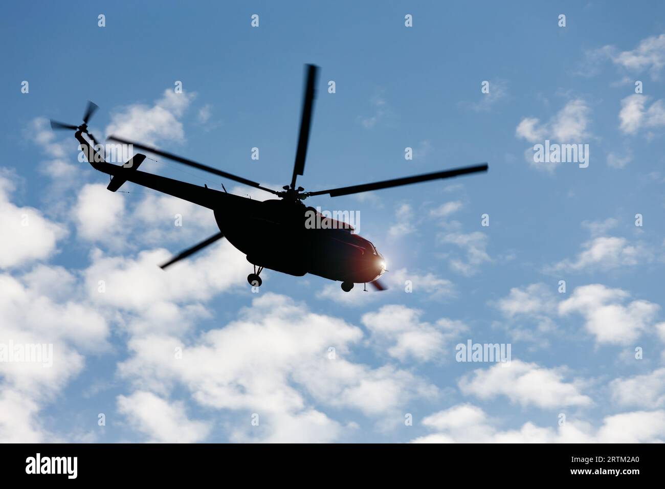 Die Silhouette des Mi-8-Hubschraubers vor dem blauen Himmel mit Wolken im Flug. Stockfoto
