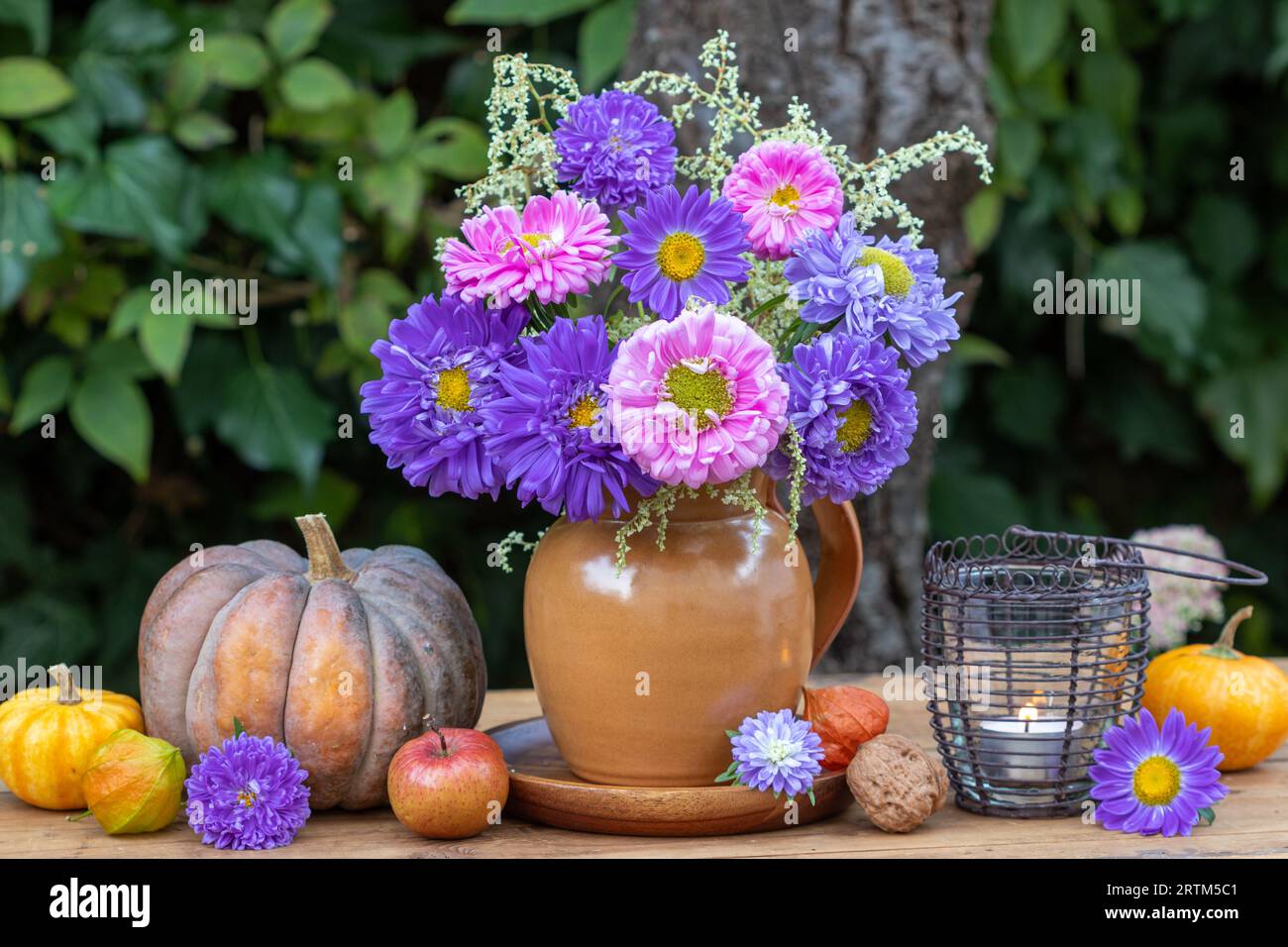 blumenarrangement mit einem blumenstrauß aus rosa und violetten Astern in einer rustikalen Vase Stockfoto