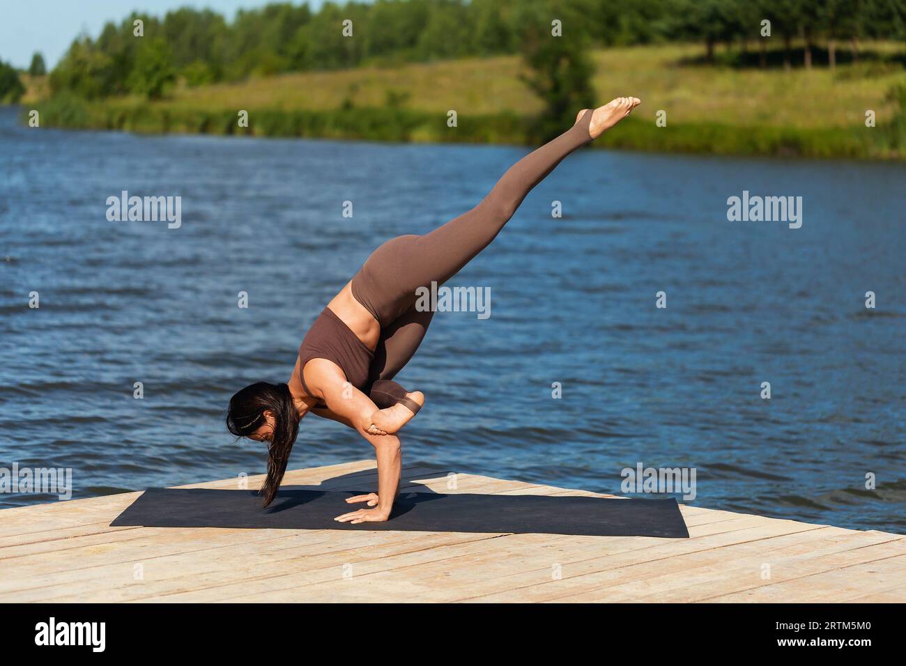 Frau, die Yoga praktiziert, Eka Pada Bakasana Übung durchführt, Kranhaltung mit nach oben gestrecktem Bein, Balance Asana, Handstand, Training allein im Sport Stockfoto