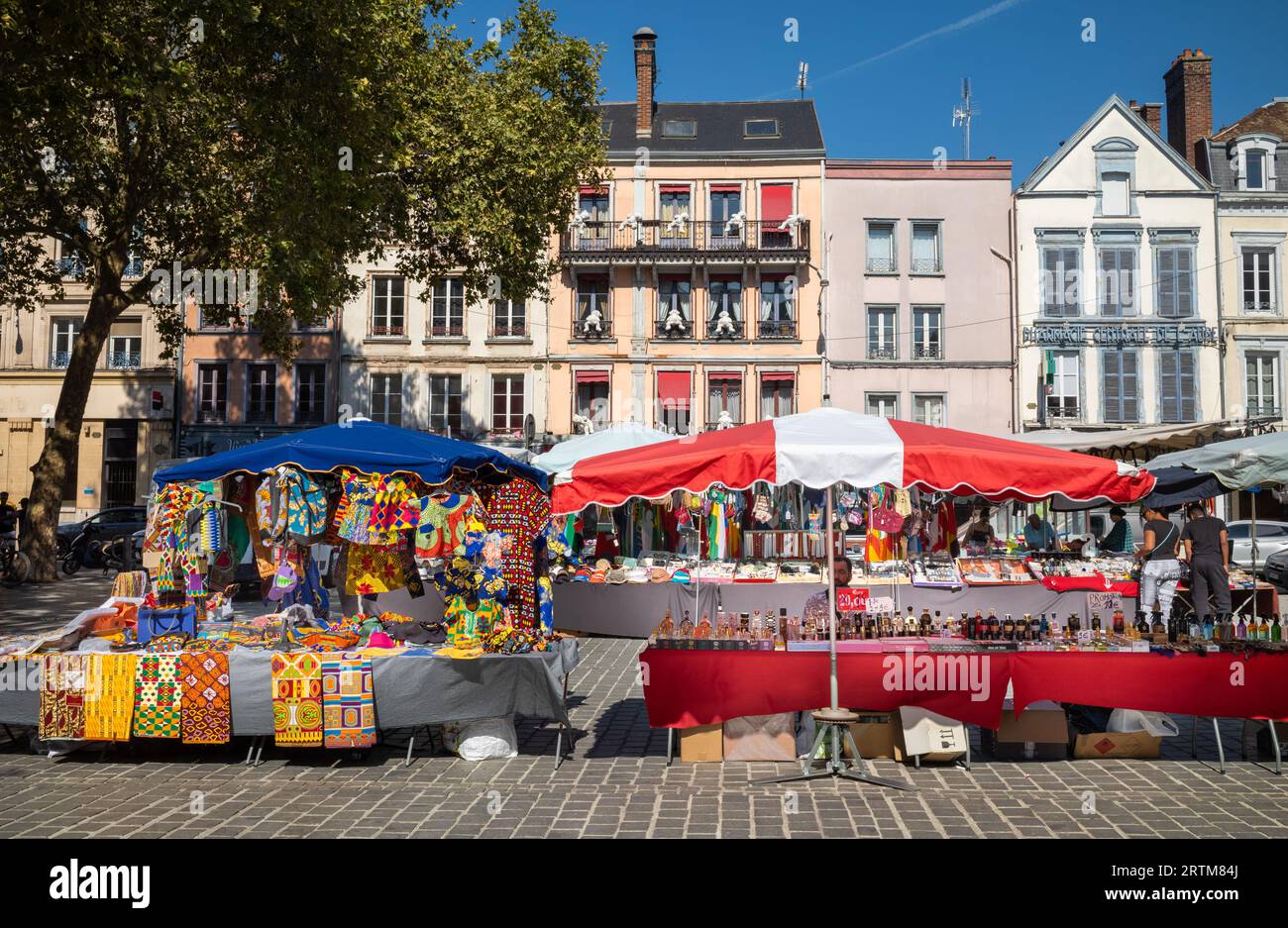 Traditionelle Häuser hinter farbenfroher Kleidung im afrikanischen Stil, die neben einem Parfümstand vor dem Zentralmarkt (Marken des Halles) in TR verkauft werden Stockfoto