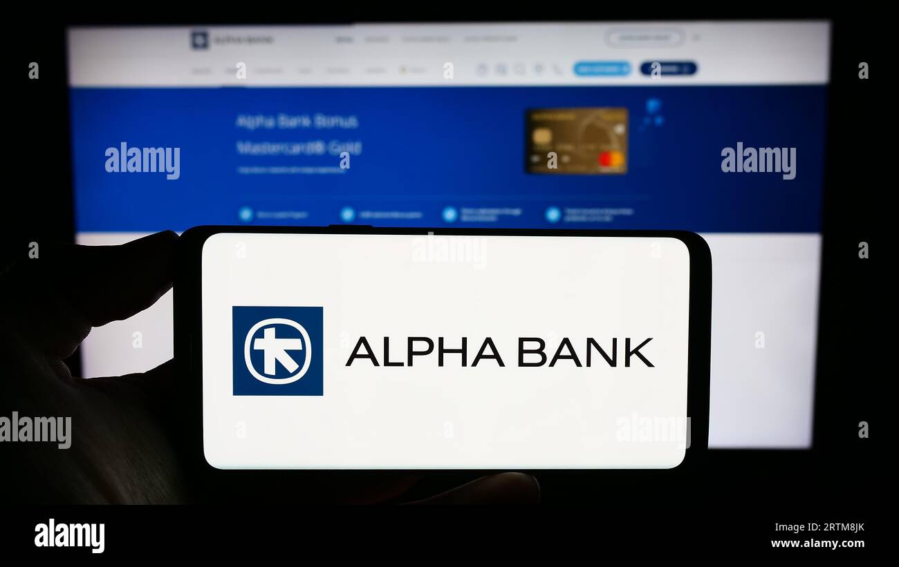 Person, die ein Mobiltelefon mit dem Logo des griechischen Finanzunternehmens Alpha Bank Group auf dem Bildschirm vor der Geschäftswebsite hält. Konzentrieren Sie sich auf das Display des Telefons. Stockfoto
