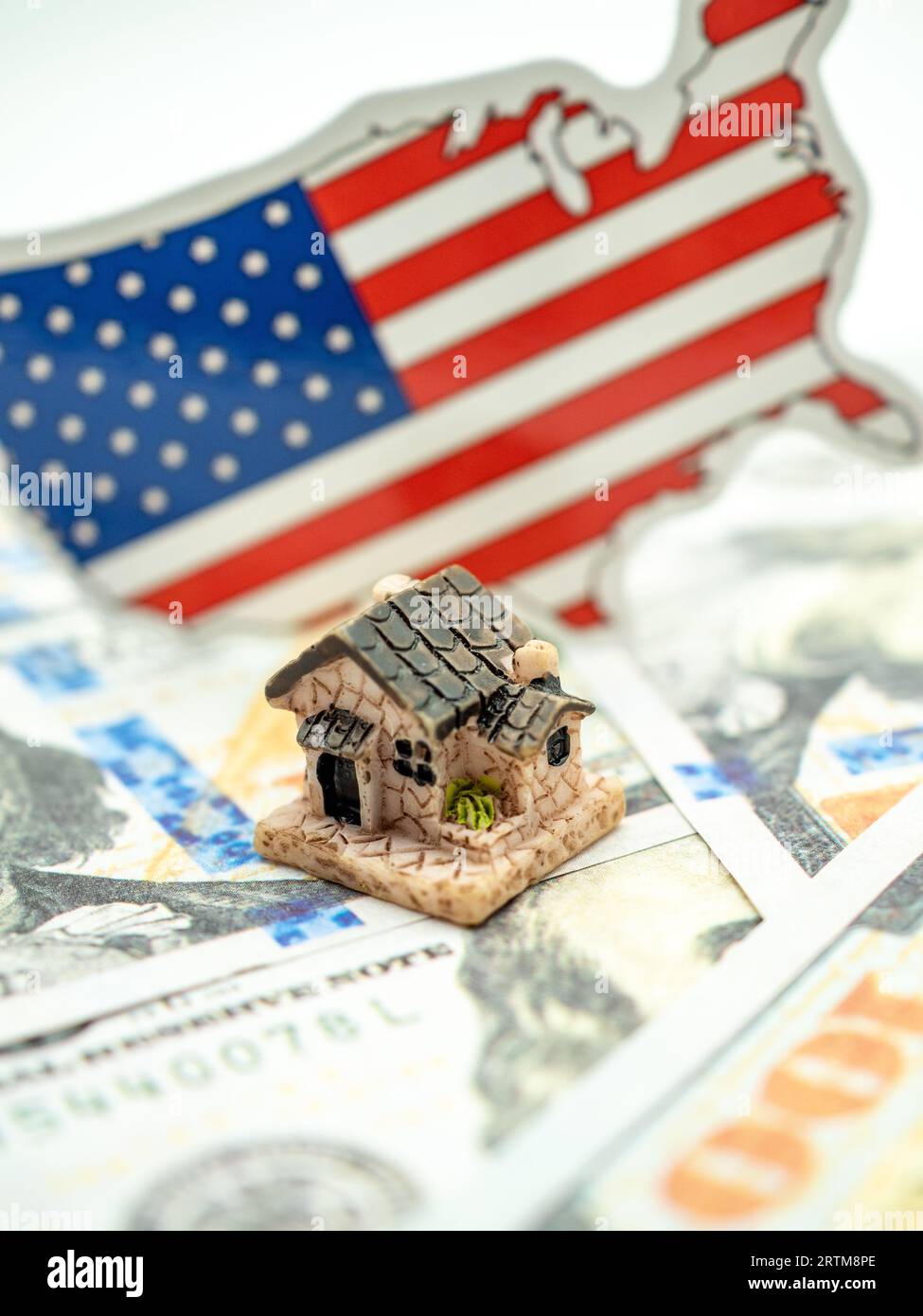 Ein kleines Haus mit einer amerikanischen Flagge auf dem Hintergrund mit Dollarnoten Stockfoto