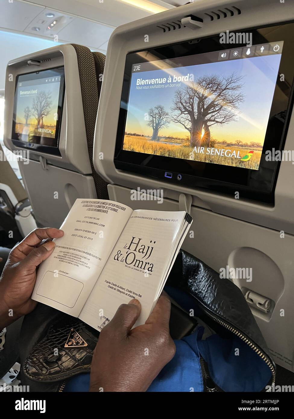 Muslimischer Passagier liest Informationen über die Pilgerfahrt auf einem Flug der Air Senegal am Flughafen Paris-CDG, Roissy-en-France Stockfoto