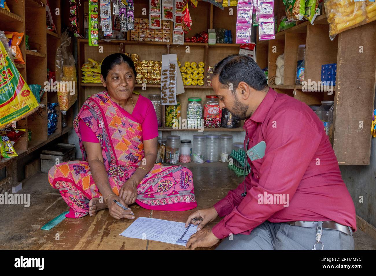 Adivasi-Ladenbesitzer mit Mitarbeitern der Mikrofinanzagentur in Dediapada, Gujarat, Indien Stockfoto