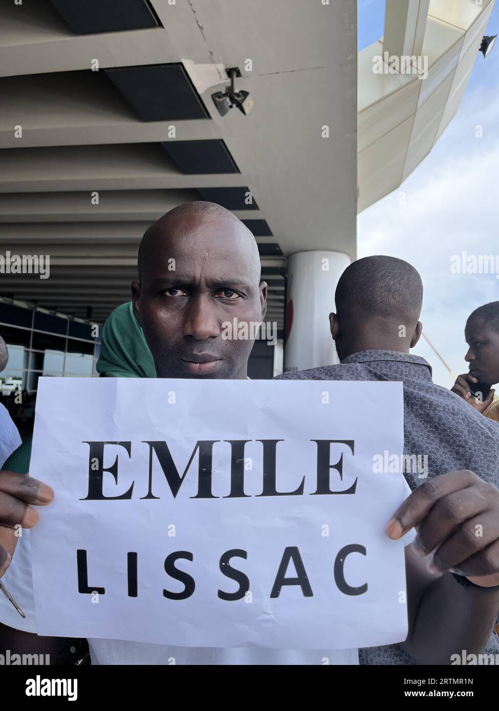 Fahrer, der ein Blatt Papier mit dem Namen seines Kunden vor dem Flughafen Blaise Diagne, Senegal, hält Stockfoto