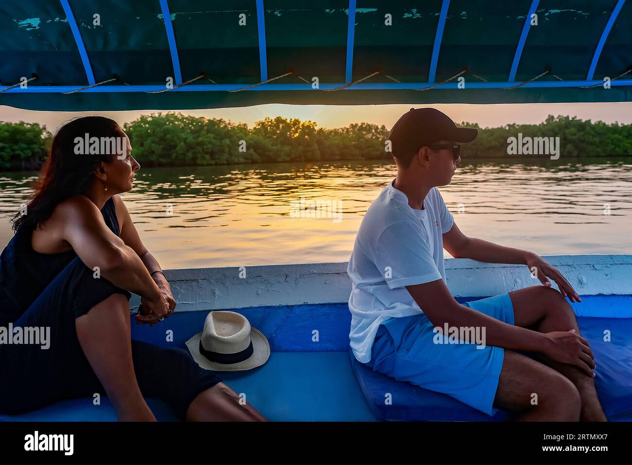 Mutter und Sohn auf einem Boot, das in der Abenddämmerung im Delta des Saloum-Flusses im Senegal fährt Stockfoto
