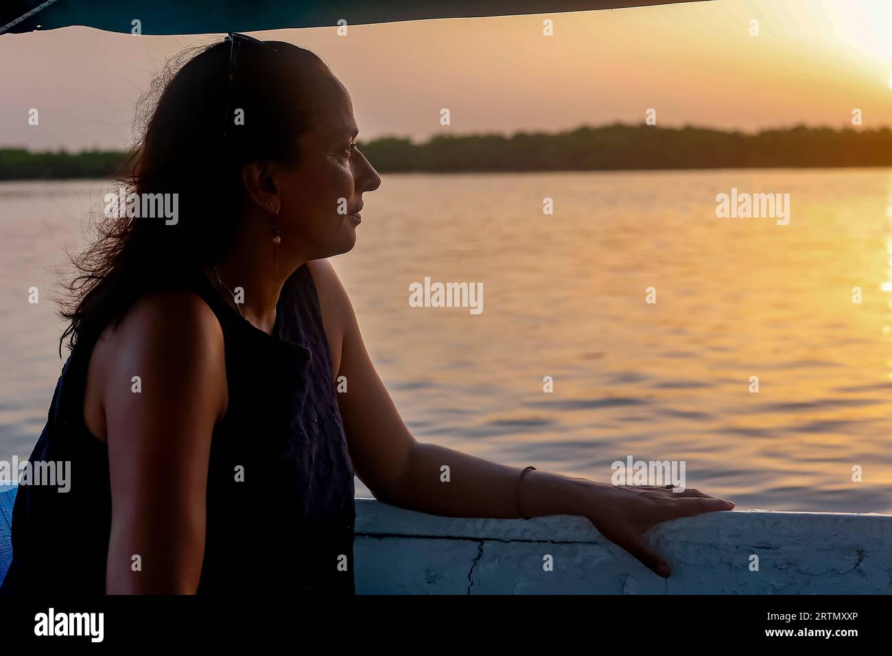 Frau auf einem Boot, das in der Abenddämmerung im Delta des Saloum-Flusses kreuzt, Senegal Stockfoto Frau auf einem Boot, das in der Abenddämmerung im Delta des Saloum-Flusses kreuzt, Senegal Stockfoto