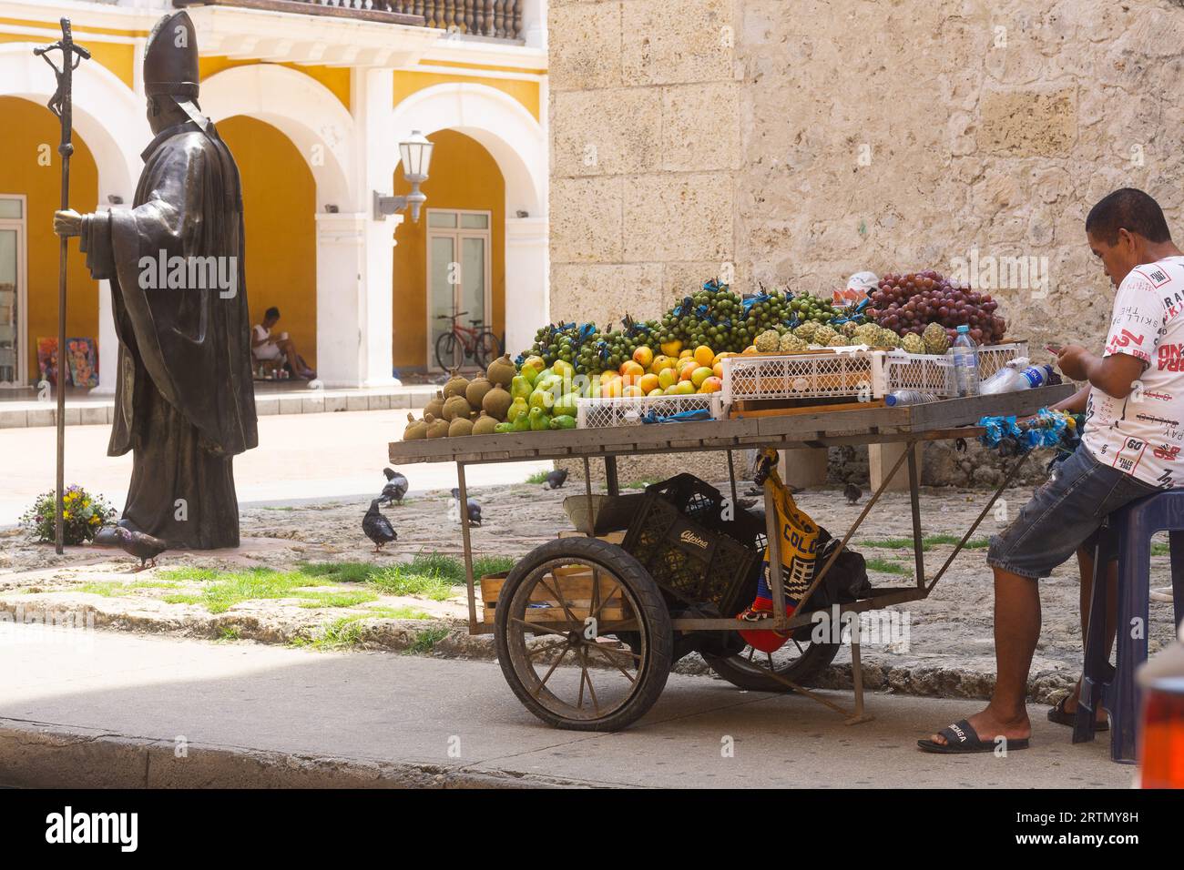 Obstverkäufer neben der Statue von Papst Johannes Paul II. In Cartagena, Kolumbien. Stockfoto