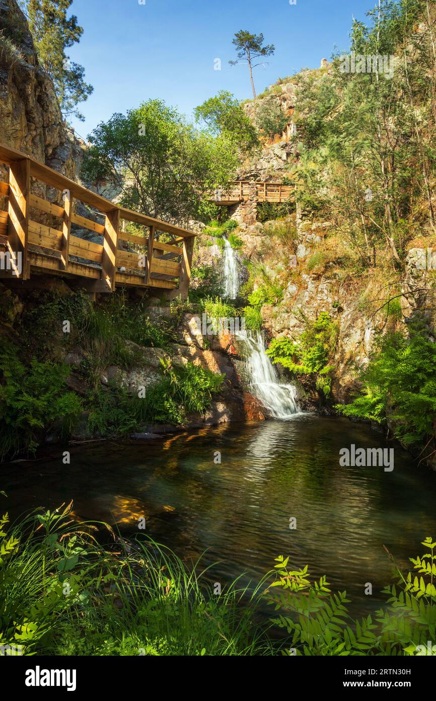 Schöner Penedo Furado Wasserfall in Vila de Rei, Portugal, mit einem natürlichen Pool umgeben von Vegetation und Holzstegen. Stockfoto