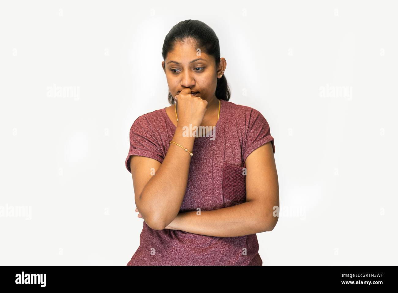 Ein Nahaufnahme-Porträt einer traurigen Frau, die nach unten schaut und ihre Hand in ihr Kinn steckt. Sie ist offensichtlich von etwas beunruhigt, und ihr Gesichtsausdruck ist o Stockfoto