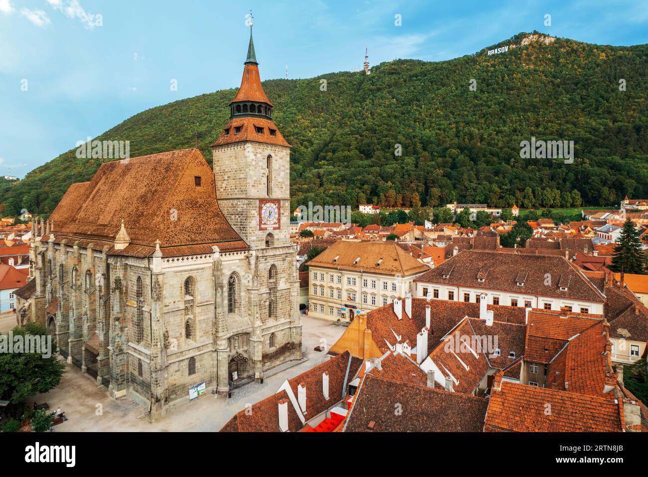 Luftaufnahme der Schwarzen Kirche im alten Brasov-Zentrum, Rumänien. Alte Wohnhäuser um sie herum, Hügel mit Grün Stockfoto Luftaufnahme der Schwarzen Kirche im alten Brasov-Zentrum, Rumänien. Alte Wohnhäuser um sie herum, Hügel mit Grün Stockfoto