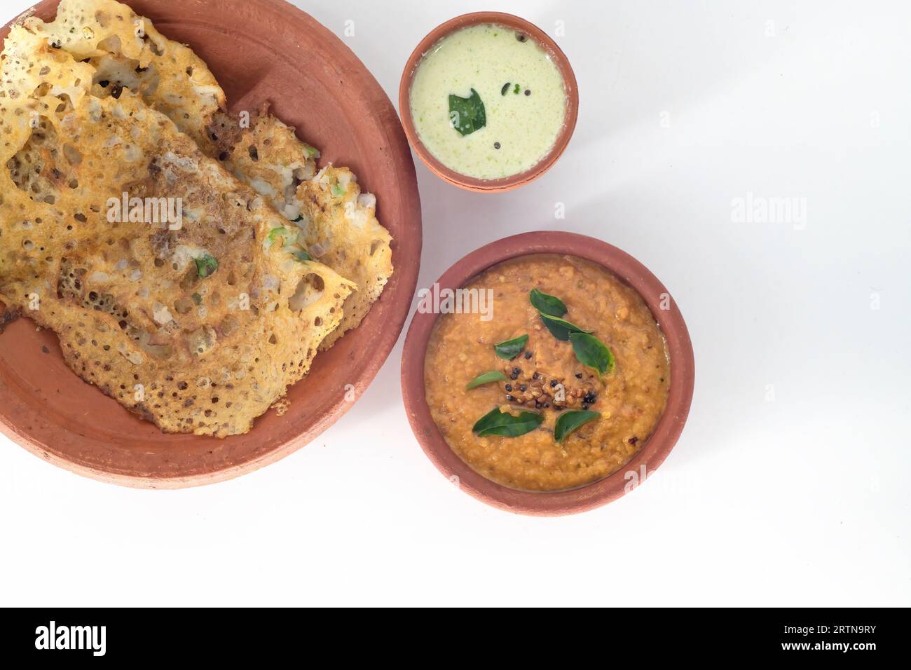 Selektiv fokussiertes indisches Rava Dosa und Tomaten-Chutney, Kokos-Chutney mit auf Schlammplatte serviert auf traditionelle Weise. Blick von oben auf indisches Frühstück Stockfoto