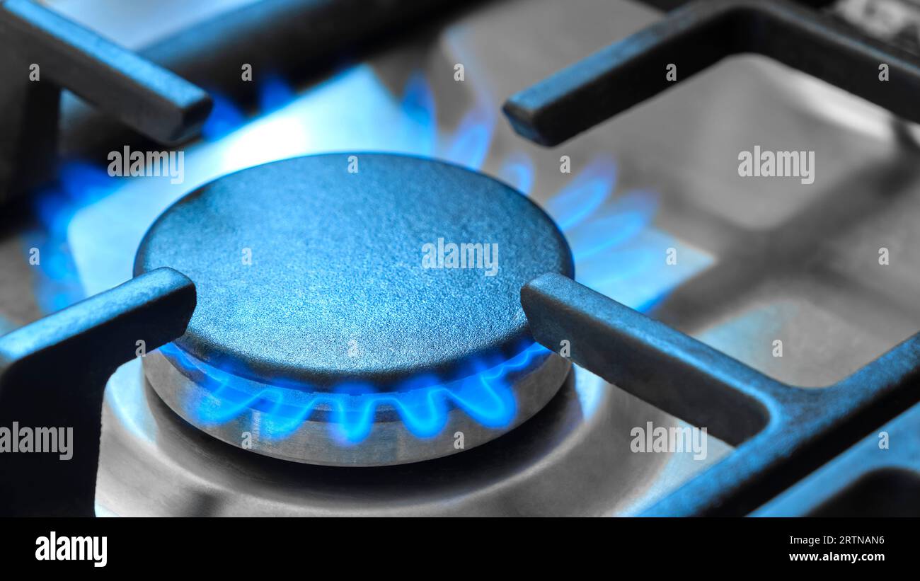 Nahaufnahme der blauen Flammen aus einem Gasherd in einer Küche. Gasherd mit brennenden Flammen von Erdgas. Konzept fossiler Brennstoffe und nicht erneuerbarer Energieträger Stockfoto