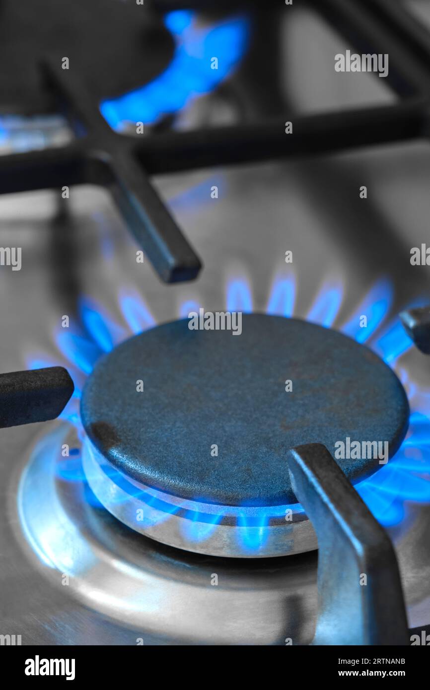 Nahaufnahme der blauen Flammen aus einem Gasherd in einer Küche. Gasherd mit brennenden Flammen von Erdgas. Konzept fossiler Brennstoffe und nicht erneuerbarer Energieträger Stockfoto