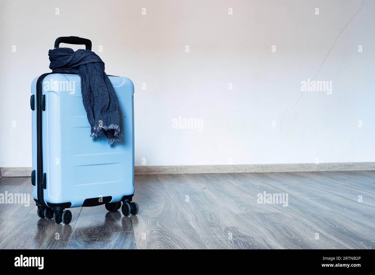Blaue Reisetasche auf Rädern mit Schal um den Griff. Copyspace, Hintergrund Stockfoto