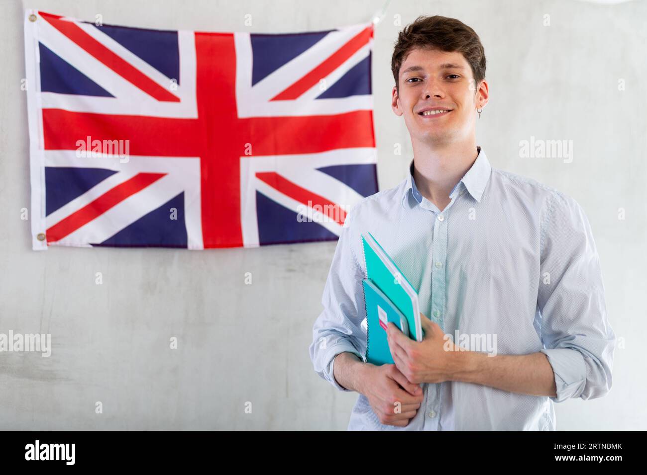 Männlicher Student mit Notizbüchern in den Händen vor dem Hintergrund der britischen Flagge Stockfoto
