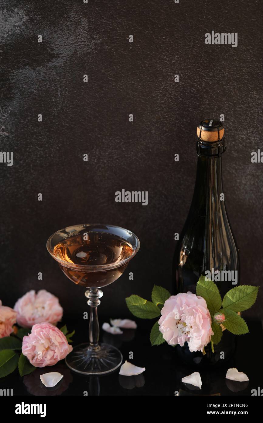 Glas rosa Champagner mit Rosenblüten auf schwarzem Hintergrund Stockfoto
