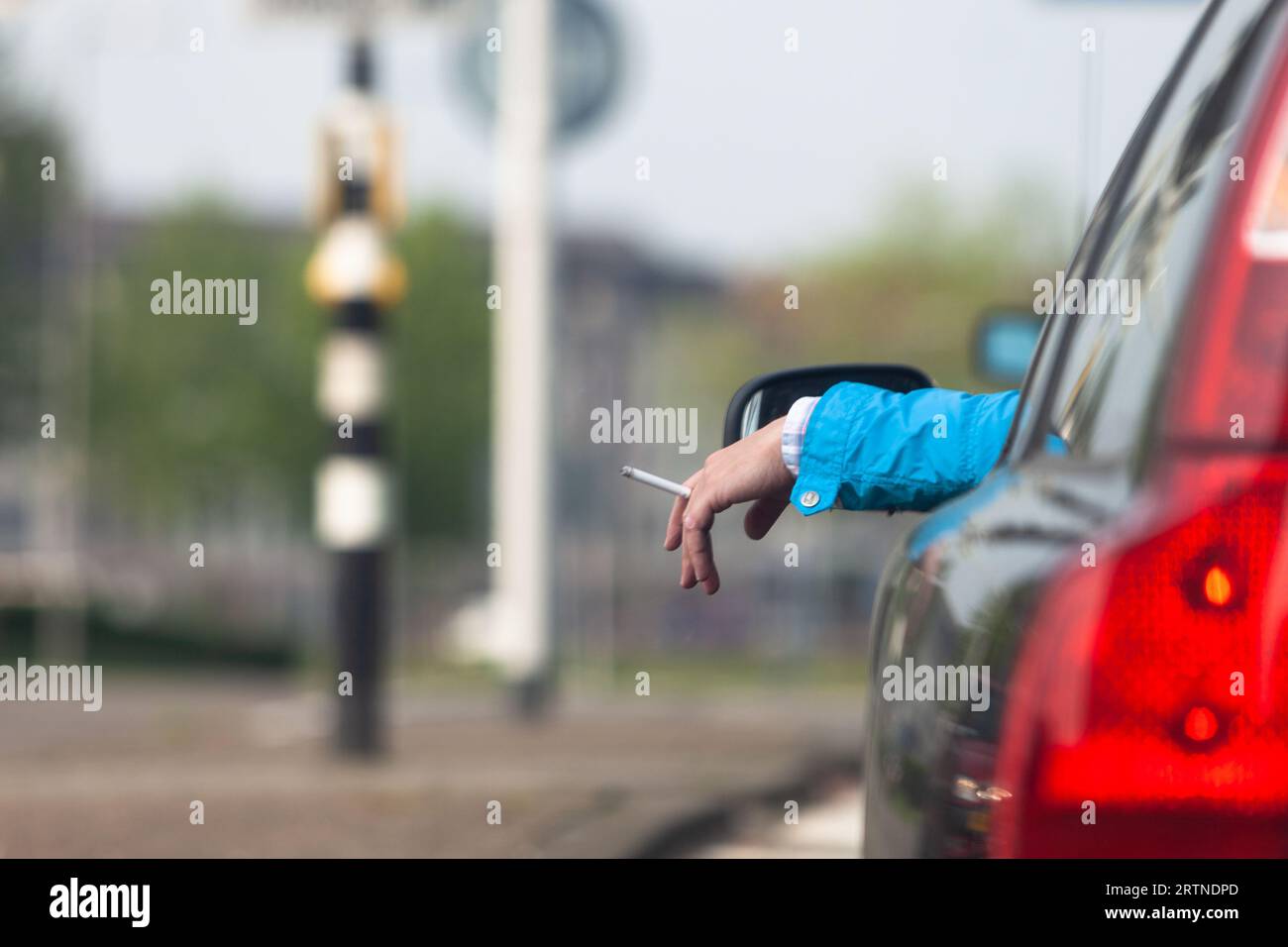 Zwangloses Rauchen einer Zigarette an einer roten Ampel in einem volvo. Stockfoto
